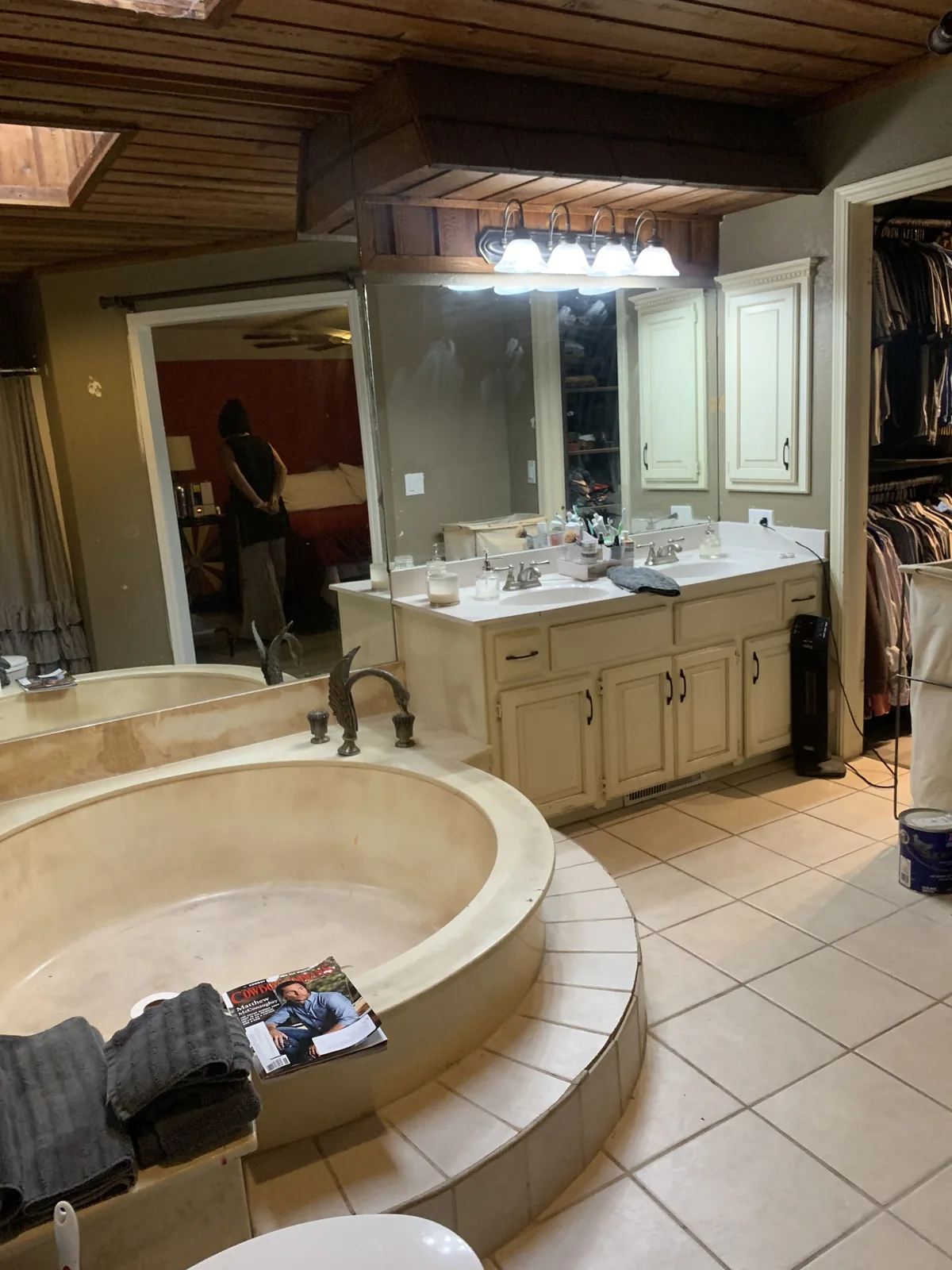 Master bathroom vanity before the remodel: cream cabinets, a wide mirror and a wood ceiling