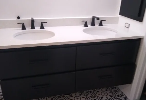 Bathroom remodeling: a black double vanity with a white quartz top and black faucets on a patterned tile floor