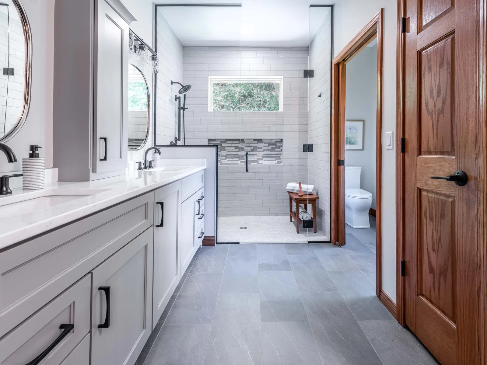 Bathroom remodeling with a light gray double vanity, a tiled walk in shower and gray tile floor