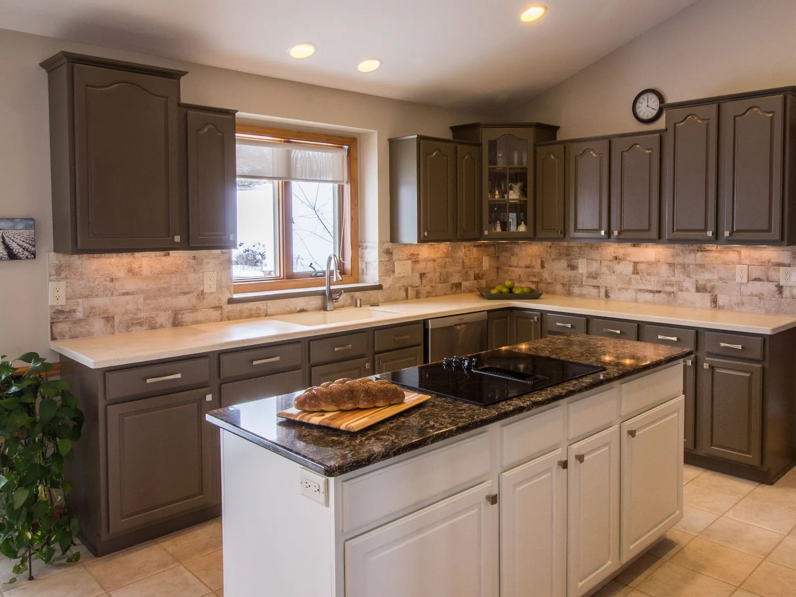 Home remodeling: a remodeled kitchen with painted gray cabinets, a stone look tile backsplash and a white island