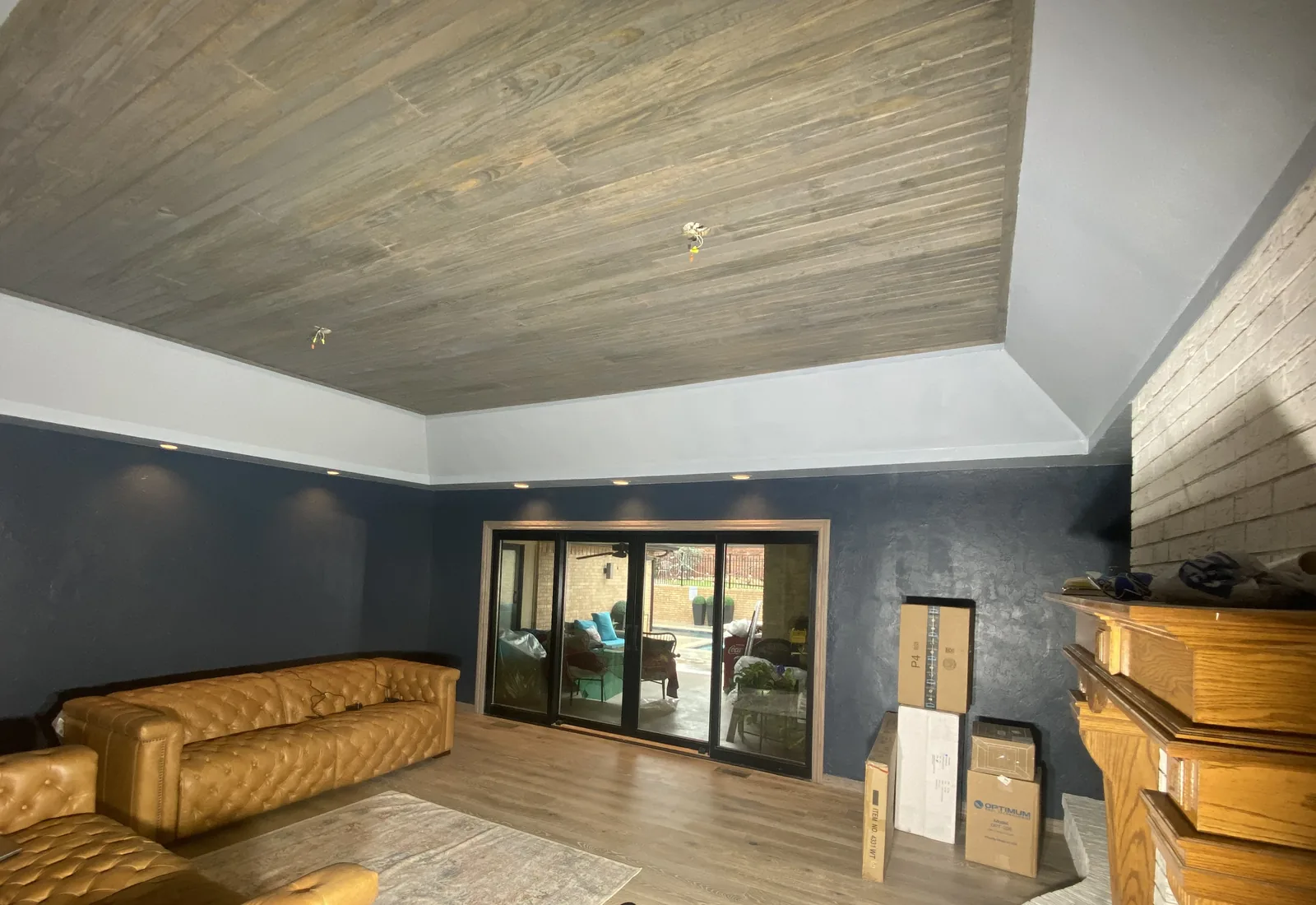 Home remodeling: a living room with a new wood plank tray ceiling, navy walls and recessed lighting