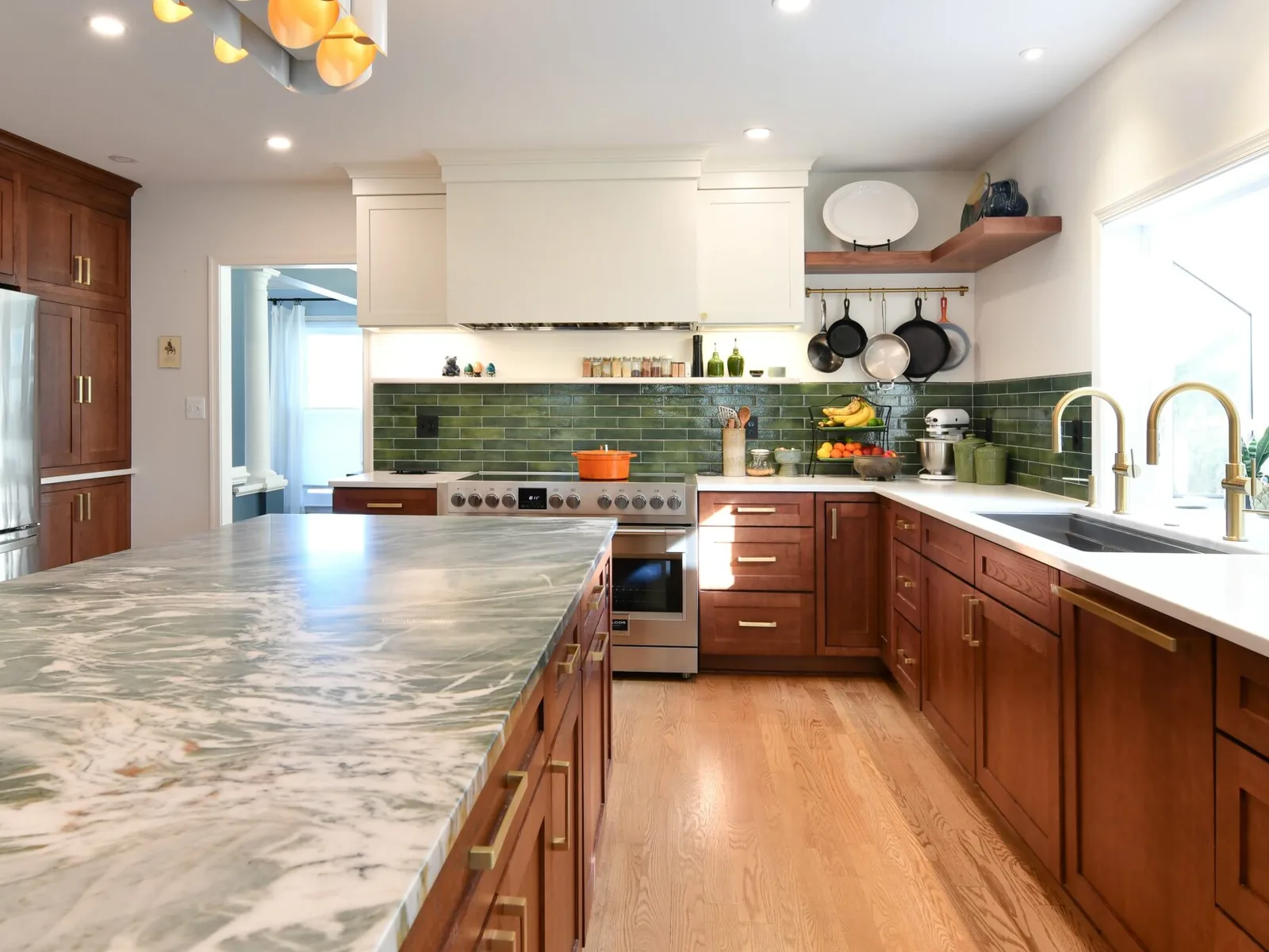 Kitchen remodeling with cherry cabinets, a green subway tile backsplash and a large marble look island