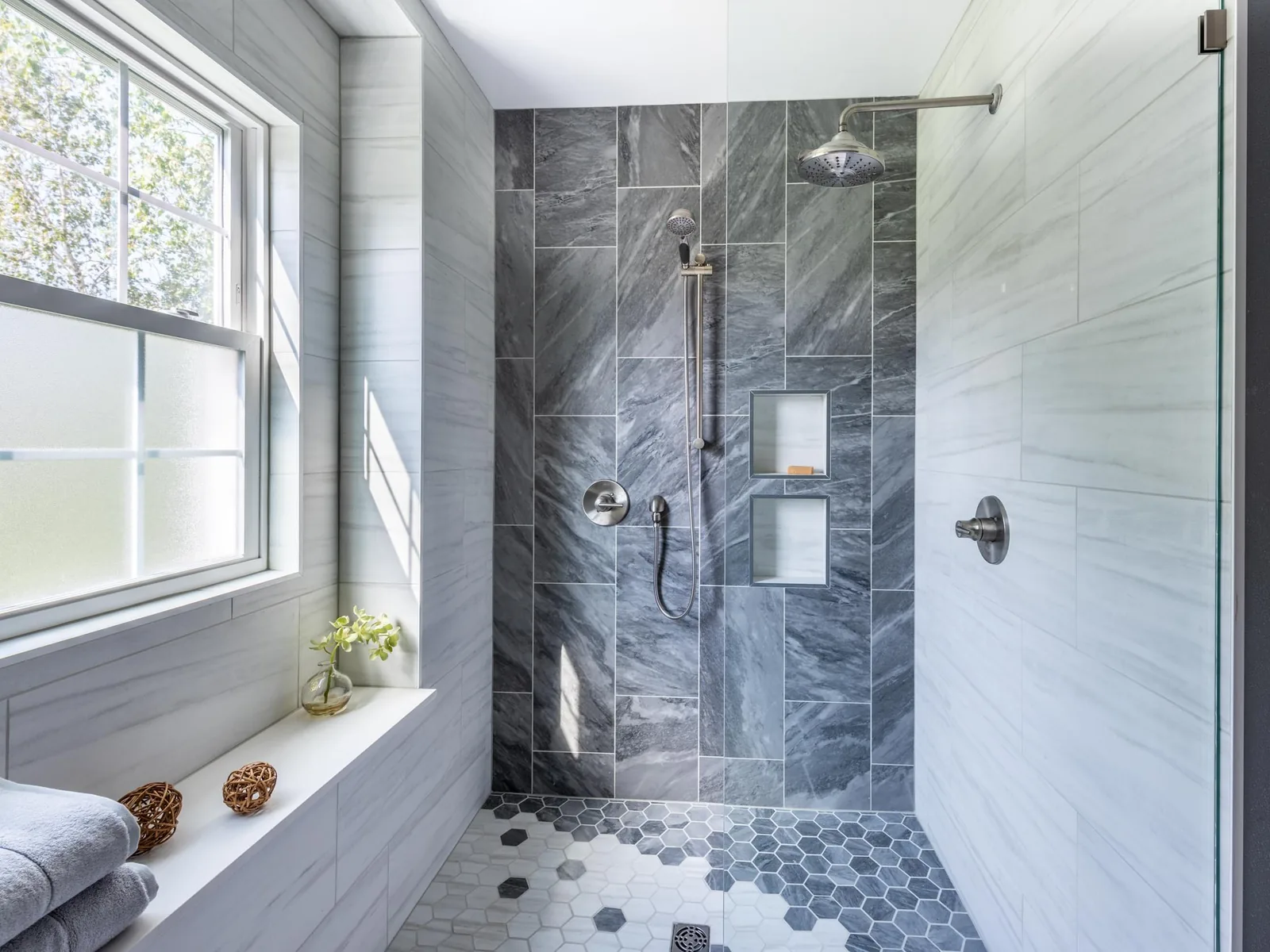 Shower remodel with a doorless walk in tile shower, a gray tile feature wall and a hexagon tile floor