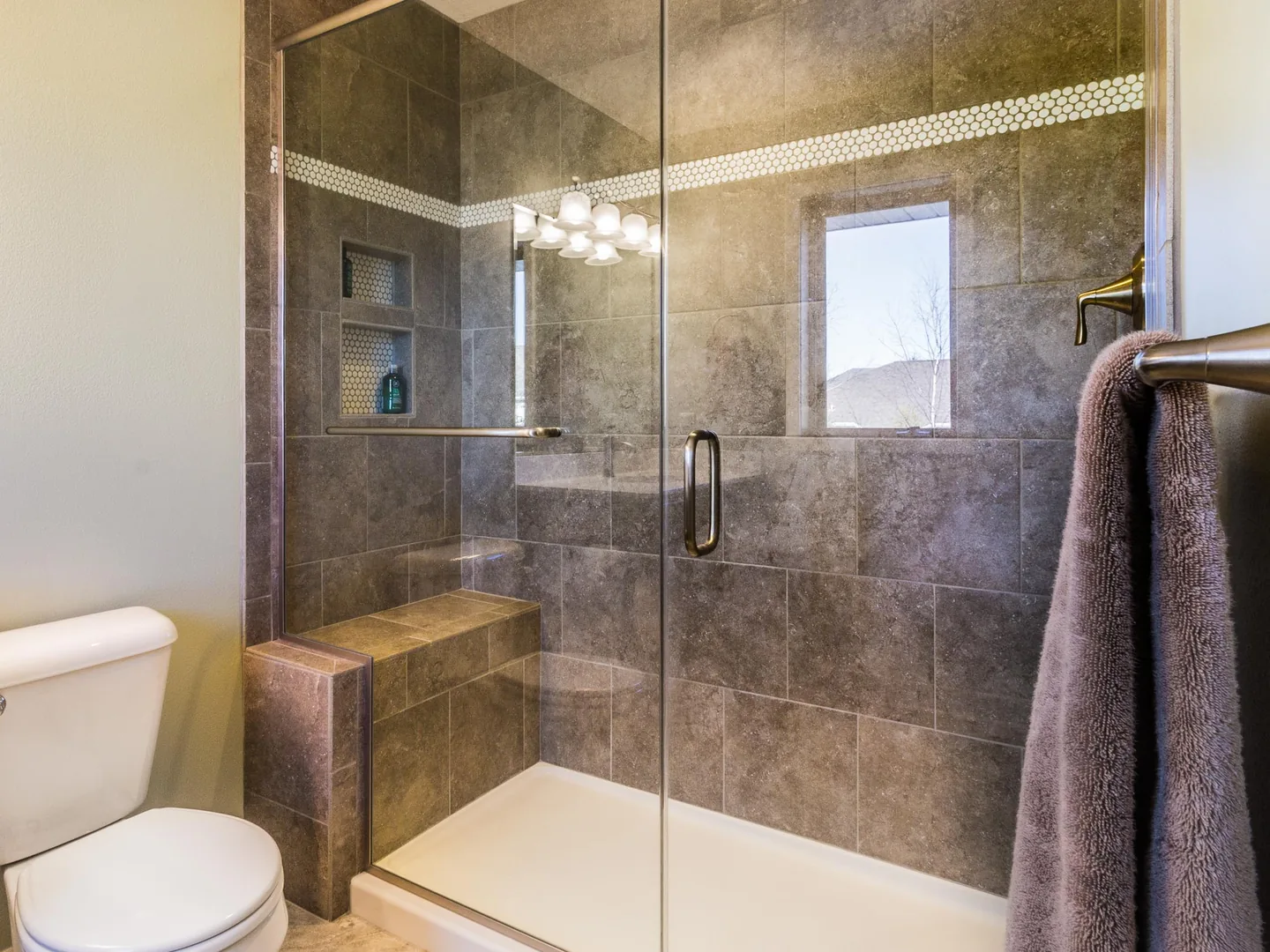 Shower remodel with a glass door, a built in tile bench and two wall niches
